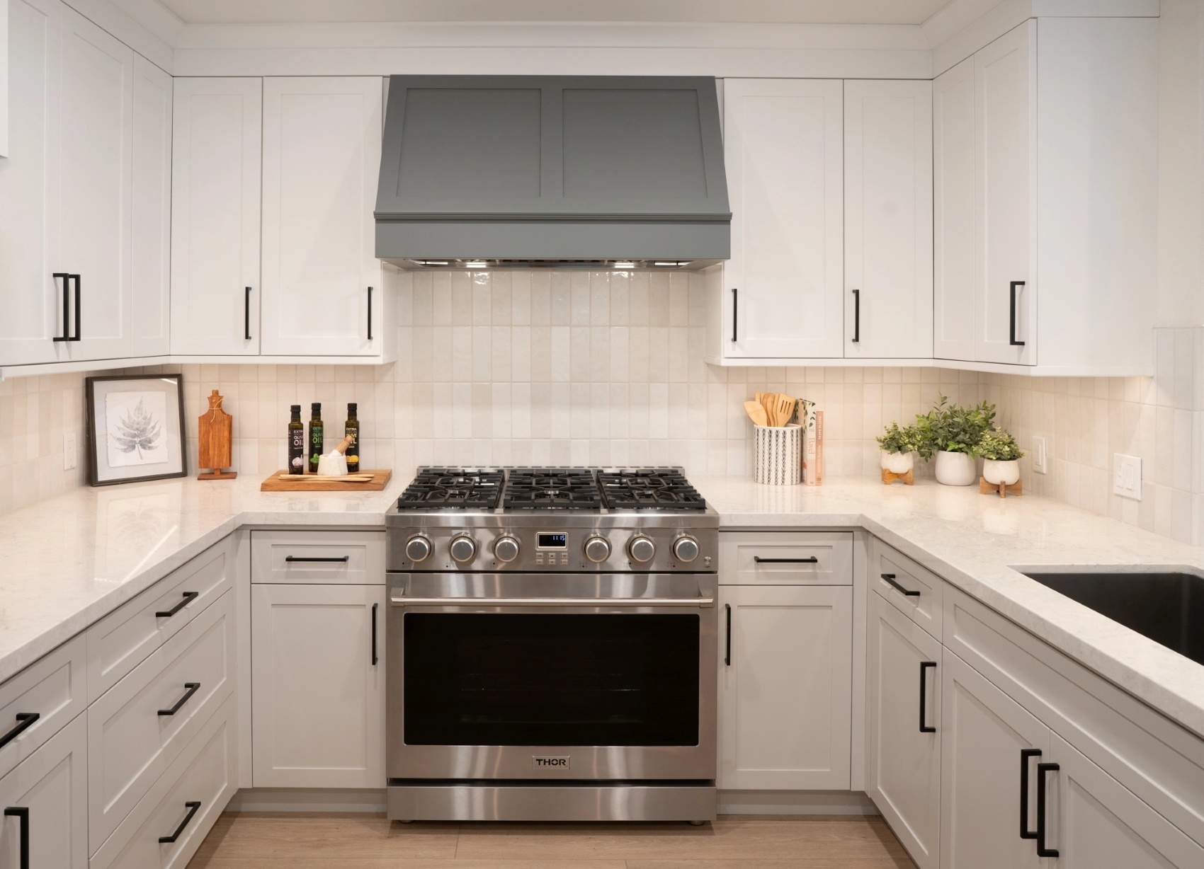 U shaped kitchen with white cabinets and stainless steel stove