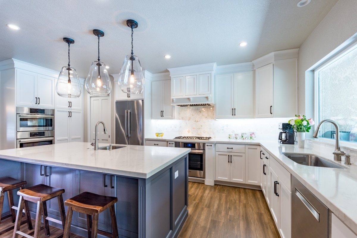 white kitchen with blue island and pendant lights